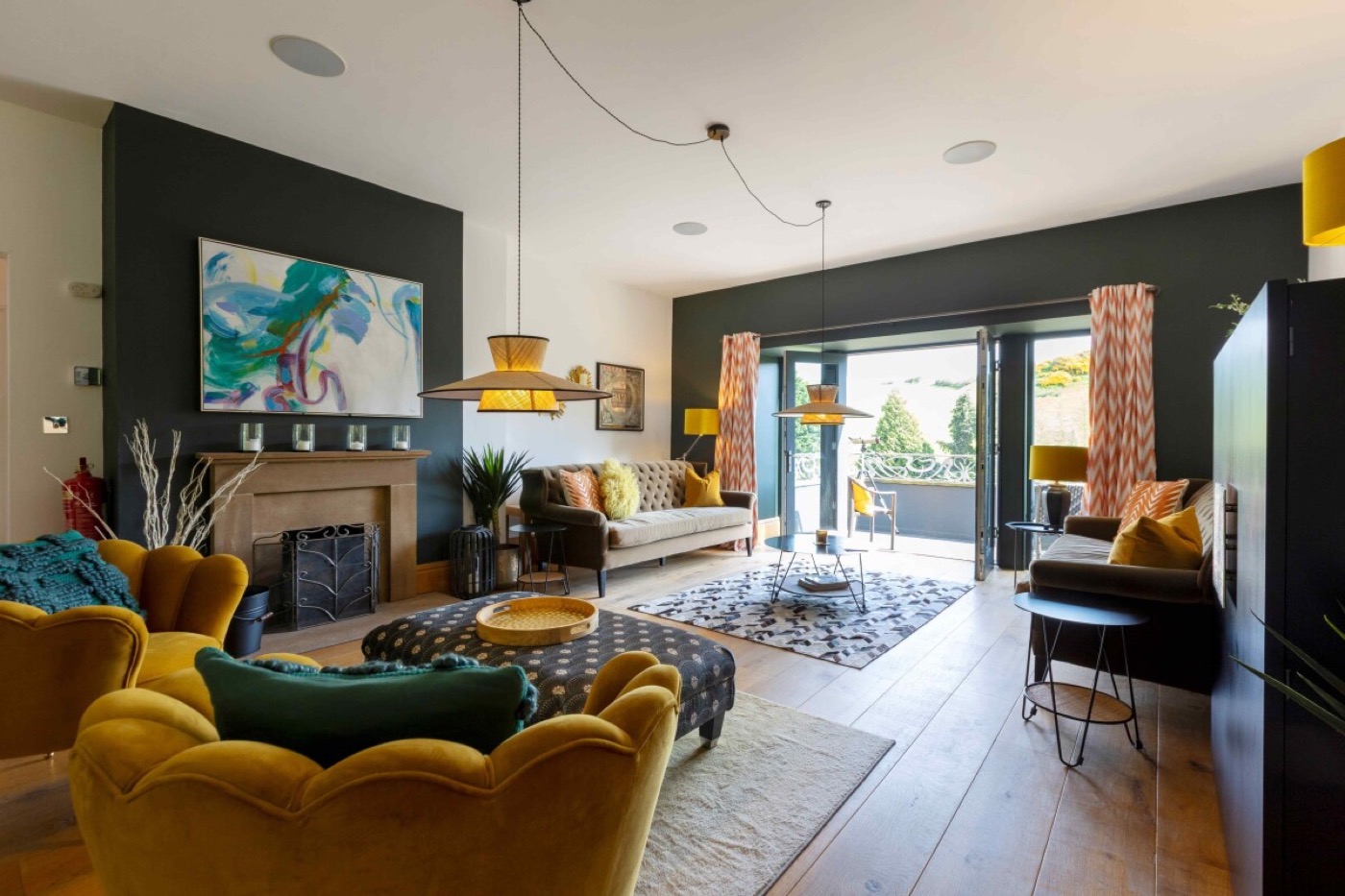 The snug at the Lake House: mustard velvet chairs, dark teal walls and a big abstract painting